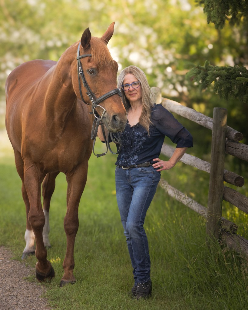 photographer and her horse standing next to a fence with trees behind